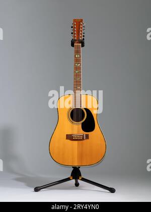 Joodee akustische 12-saitige Gitarre auf einem Ständer auf grauem Hintergrund mit Schatten Stockfoto