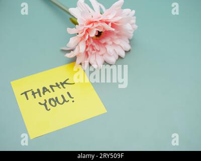 Draufsicht auf die Worte Dankeschön auf Haftnotiz mit Blumen daneben Stockfoto