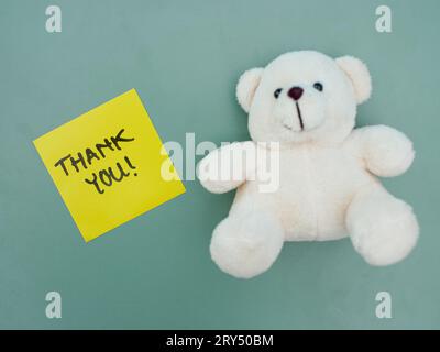 Ansicht von oben: Dankeschön auf Haftnotiz mit weißem Teddybär daneben Stockfoto