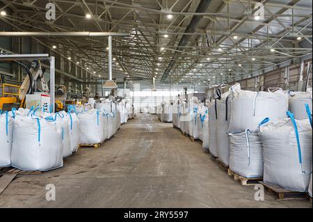 Riesige Plastiktüten mit Produkten auf Paletten in der Recyclingfabrik Stockfoto