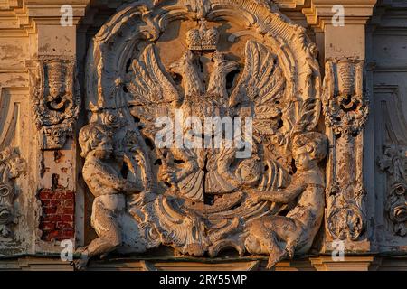 Dekoratives Element mit dem Wappen Russlands in Form eines Doppeladlers mit einer Krone an der Hauptfassade des Znamenski-Palastes. Schloss Znamensky ist ein Schloss- und Parkensemble der Architekten Bosse, Stackenschneider, Erler. Der Palast des Großherzogs Nikolai Nikolaevich, östlich von Peterhof. Der Palast im neobarocken Stil, die Peter-Paul-Kirche, der Stallhof, das Küchengebäude und die Gewächshäuser sind bis heute erhalten. Der Palast hat den Status eines UNESCO-Weltkulturerbes. Nach der Revolution befanden sich sowjetische Institutionen im e Stockfoto