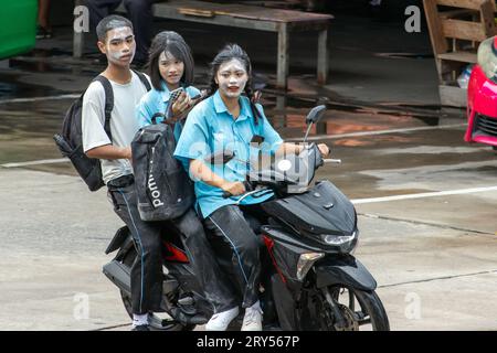 SAMUT PRAKAN, THAILAND, Juni 06 2023, Ein Trio von Teenagern mit Puder auf ihren Gesichtern, die mit einem Motorrad im Regen fahren Stockfoto