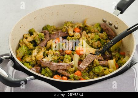 Rindfleisch und Brokkoli mit Bratensoße Rezept. Köstliche Mahlzeit in einer Pfanne zubereitet, Nahaufnahme auf dem Küchentisch Stockfoto