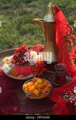 Orientalische Süßigkeiten mit Kupferkrug auf rotem Hintergrund Stockfoto