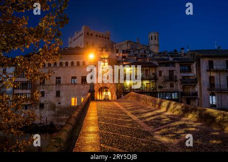 Burg und Kirche von Valderrobres, beleuchtet zur blauen Stunde und in der Nacht, von der Brücke über den Fluss Matarraña (Teruel, Aragon, Spanien) aus gesehen Stockfoto