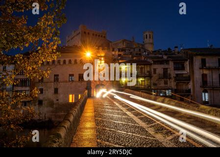 Burg und Kirche von Valderrobres, beleuchtet zur blauen Stunde und in der Nacht, von der Brücke über den Fluss Matarraña (Teruel, Aragon, Spanien) aus gesehen Stockfoto