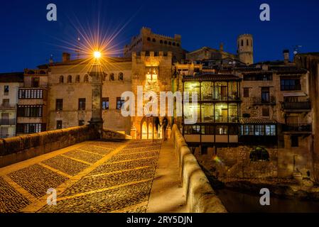 Burg und Kirche von Valderrobres, beleuchtet zur blauen Stunde und in der Nacht, von der Brücke über den Fluss Matarraña (Teruel, Aragon, Spanien) aus gesehen Stockfoto