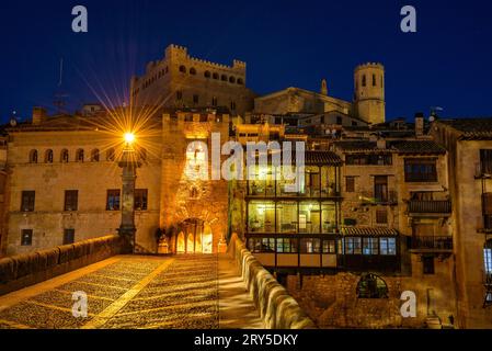 Burg und Kirche von Valderrobres, beleuchtet zur blauen Stunde und in der Nacht, von der Brücke über den Fluss Matarraña (Teruel, Aragon, Spanien) aus gesehen Stockfoto