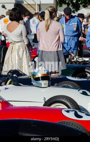 Bei der Motorsport-Veranstaltung Goodwood Revival mit alten Rennautos tragen die Besucher eine alte Kleidung. Frauen mit Grand-Prix-Fahrzeugen aus der Zeit der 1930er Jahre im Montagebereich Stockfoto