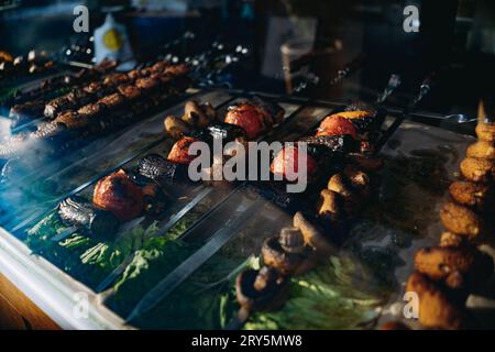 Traditioneller kaukasischer Schisch-Kebab auf dem Street Food Market. Gegrillte Champignons, Tomatos und anderes Gemüse Stockfoto