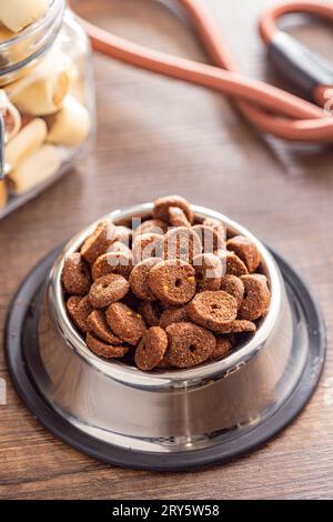 Trockenes Tierfutter. Hunde- oder Katzenkibbeln isoliert in der Schüssel auf dem Holztisch. Stockfoto