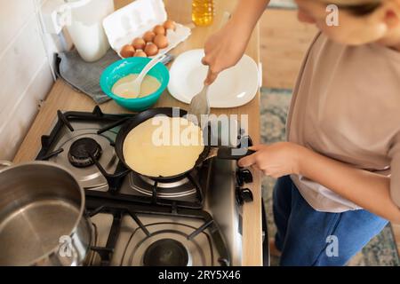 Eine Frau macht Pfannkuchen auf einer Grillplatte Stockfoto