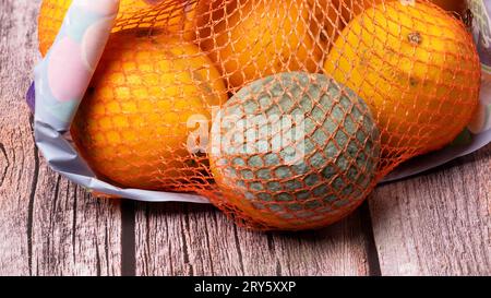 In einem Netzbeutel mit Orangen befindet sich eine verdorbene Orange mit Schimmel. Stockfoto