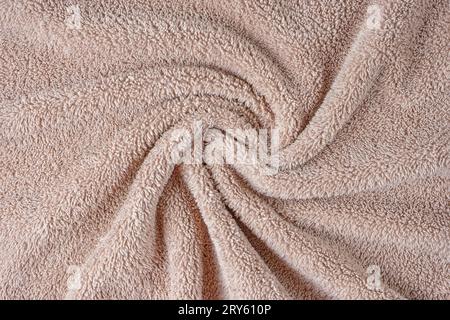 Frottee, beigefarbener Handtuchhintergrund. Zerknittertes und zerknittertes, weiches, flauschiges Textil-Bad- oder Strandhandtuchmaterial. Draufsicht, Nahaufnahme. Stockfoto