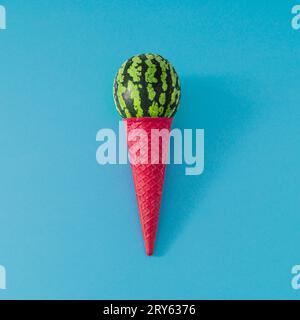 Eis aus rosafarbenem Waffel-Eiskegel und einer Schaufel Wassermelonenfrucht auf hellblauem Hintergrund. Sommereiskomposition. Minimales Konzept. Stockfoto
