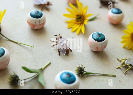 halloween-Muster mit Insekten, Augäpfeln und wilden Sonnenblumen auf hellem Hintergrund Stockfoto