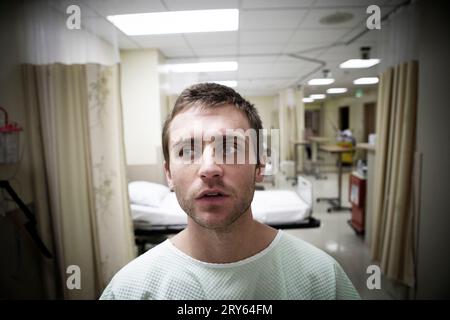 Ein Porträt eines jungen Mannes, der in einem Krankenhauszimmer sitzt. Stockfoto
