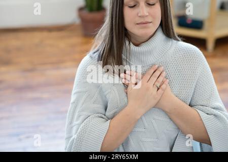 Nahaufnahme einer Frau, die mit den Händen am Herzen meditiert Stockfoto