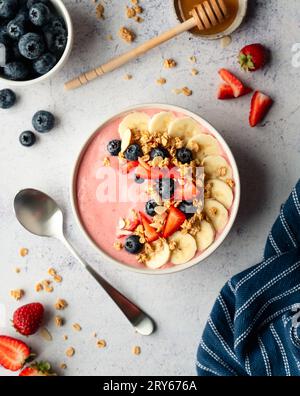 Blick von oben auf die Smoothie-Schüssel mit Obst und Müsli auf grauem Hintergrund. Stockfoto