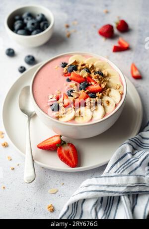 Nahaufnahme einer Smoothie-Schüssel mit Obst und Müsli auf grauem Hintergrund. Stockfoto