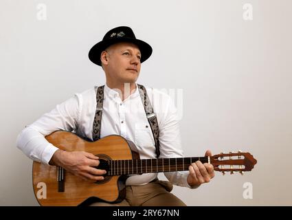 Mann mit Hut, der Gitarre spielt, grauer Hintergrund Stockfoto