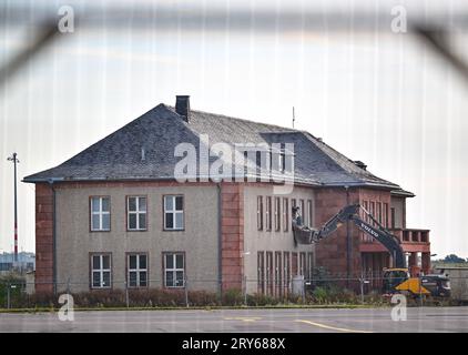 29. September 2023, Brandenburg, Schönefeld: Ein Bagger steht vor dem für den Abbruch vorgesehenen General Hotel auf dem ehemaligen Flugplatz Schönefeld, dem heutigen Flughafen Berlin Brandenburg (BER). Die Vorbereitungen für den Abriss des historischen Generalshotels auf dem Gelände des BER-Flughafens werden trotz starker Proteste von Politikern, Architekten und Denkmalschützern fortgesetzt. Nach Angaben der Bundesbehörde soll der Abriss Anfang 2024 abgeschlossen sein. Foto: Patrick Pleul/dpa Stockfoto