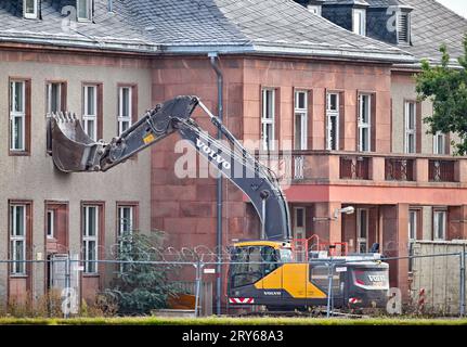 29. September 2023, Brandenburg, Schönefeld: Ein Bagger steht vor dem für den Abbruch vorgesehenen General Hotel auf dem ehemaligen Flugplatz Schönefeld, dem heutigen Flughafen Berlin Brandenburg (BER). Die Vorbereitungen für den Abriss des historischen Generalshotels auf dem Gelände des BER-Flughafens werden trotz starker Proteste von Politikern, Architekten und Denkmalschützern fortgesetzt. Nach Angaben der Bundesbehörde soll der Abriss Anfang 2024 abgeschlossen sein. Foto: Patrick Pleul/dpa Stockfoto