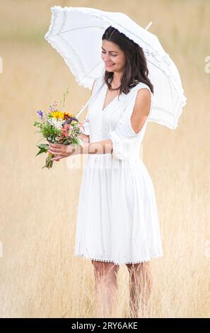 Das junge Mädchen steht mit Blumen und wartet freudig Stockfoto