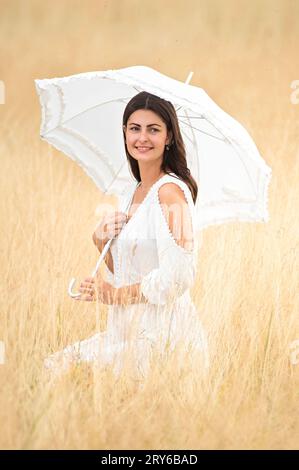 Romantische Szene mit einer jungen Frau mit Regenschirm und Kleid Stockfoto