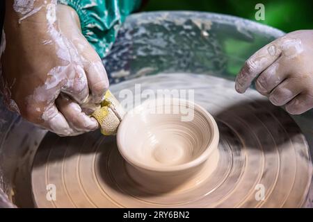 Der angehende Töpfer nimmt die Herausforderungen an, den Ton zu einem Teller zu Formen. Stockfoto