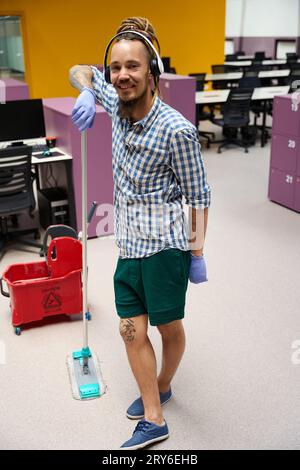 Fröhliches, ungezwungenes Stehen mitten im Coworking Space mit Mopp Stockfoto