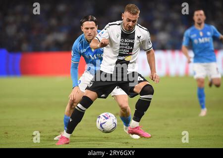 Neapel, Italien. 27. September 2023. Sandi Lovric von Udinese Calcio tritt mit Piotr Zielinski vom SSC Napoli im Spiel der Serie A zwischen den beiden um den Ball an Stockfoto