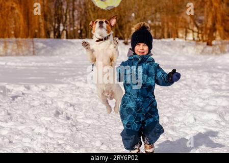 Familie spielt im Winterpark mit Hund und Ball Stockfoto