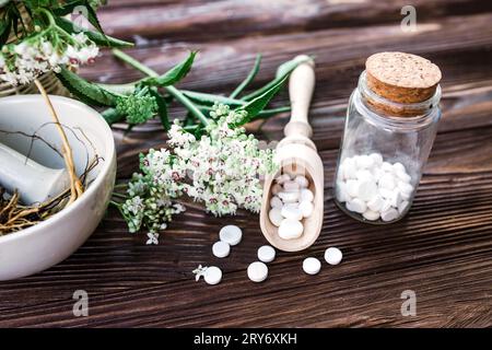 Valerian-Tabletten mit sedierenden Eigenschaften. Pharmazeutischer Becher mit Pillen auf einem Holztisch. Baldrianwurzel in einem Mörser für Herbalismus-Elixier kochen Stockfoto