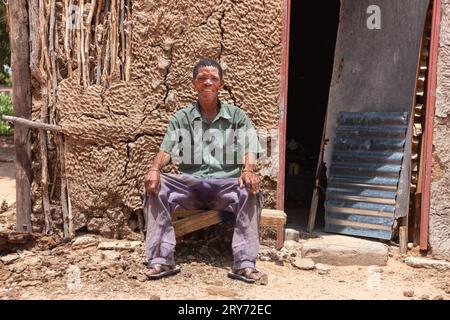 Ein alter Buschmann san man aus Zentral-Kalahari, Dorf New Xade in Botswana, vor seinem Lehmhaus nach dem Umzug Stockfoto