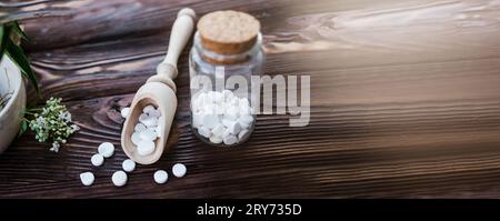 Valerian-Tabletten mit sedierenden Eigenschaften. Pharmazeutischer Becher mit Pillen auf einem Holztisch. Baldrianwurzel in einem Mörser für Herbalismus-Elixier kochen Stockfoto