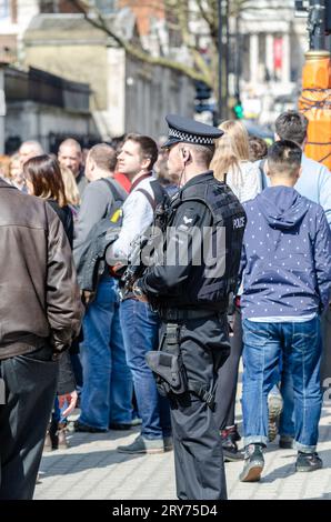 Bewaffneter Polizeibeamter in London mit Touristen vor der Pferdewache in Whitehall. Menschen. Männlicher zugelassener Feuerwaffenoffizier, umgeben von Öffentlichkeit, im Dienst Stockfoto