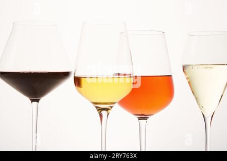 Rosafarbene, weiße, rote, prickelnde alkoholische Getränke in Weingläsern. Stockfoto