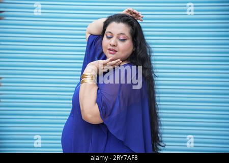 Porträt einer jungen indischen Plus-Size-Frau, die isoliert auf blauem Hintergrund steht. Stockfoto