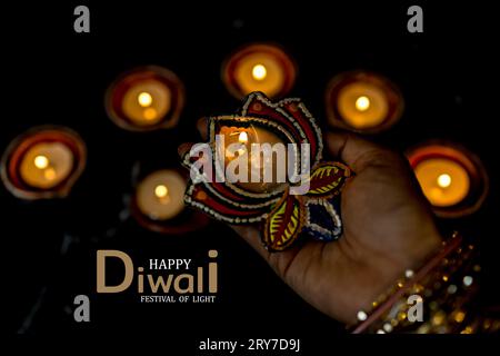 Happy Diwali - Frau Hände mit Henna halten brennende Kerze isoliert auf dunklem Hintergrund. Ton Diya Lampen während Dipavali, Hindu-Festival der Lichter ce beleuchtet Stockfoto