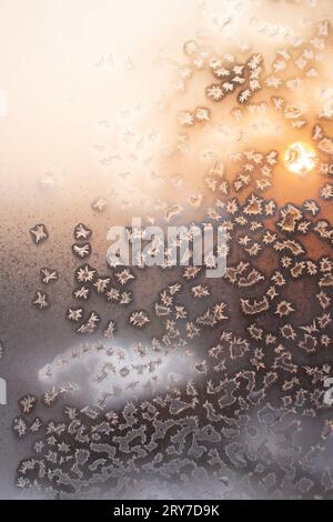 Frostige Textur auf gefrorenem Fenster bei Sonnenuntergang oder Sonnenaufgang mit Eiskristallen. Weihnachten oder Neujahr Hintergrund, Winter. Leerzeichen kopieren Stockfoto