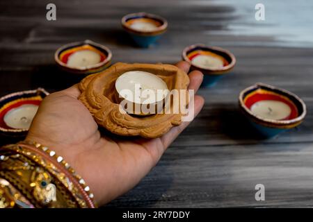 Happy Diwali - Frau Hände mit Henna halten brennende Kerze isoliert auf dunklem Hintergrund. Ton Diya Lampen während Dipavali, Hindu-Festival der Lichter ce beleuchtet Stockfoto