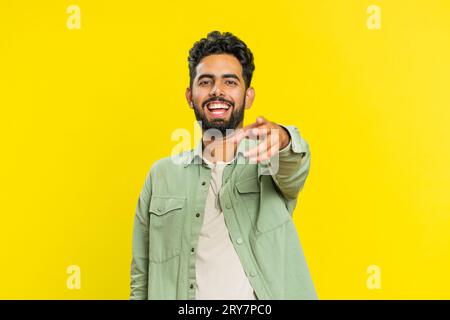 Glücklicher junger indischer Mann, der laut lacht, nachdem er lächerliche Anekdoten gehört hat, Reaktion auf lustigen Witz, unbeschwert amüsiert. Positiver Lebensstil. Arabier isoliert auf gelbem Hintergrund Stockfoto