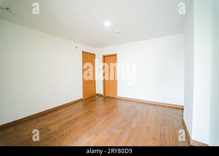 Das Zimmer ist leer und hat zwei Türen, eine an der Vorderwand und eine an der Seitenwand. Der Boden ist aus Holz und hat ein strukturiertes Aussehen. Stockfoto