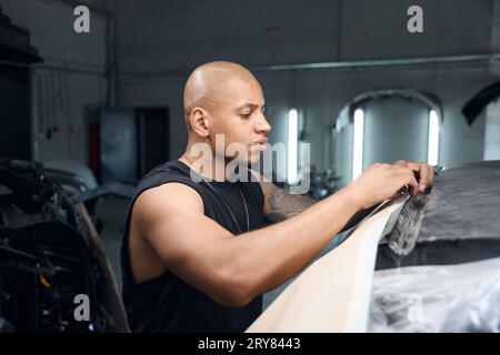 Mitarbeiter in der afroamerikanischen Autowerkstatt bereiten das Fahrzeug auf die Neulackierung vor Stockfoto