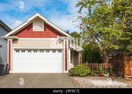 Garage mit kurzer Auffahrt an einem sonnigen Sommertag. Garagentor in Vancouver, Kanada. Moderne, breite Garagentür und Betoneinfahrt davor. Perfekt Stockfoto