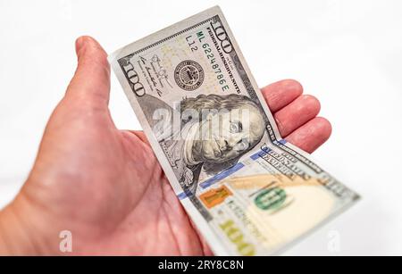 Hand hält einen Dollar isoliert auf weißem Hintergrund. Mann oder Frau geben 100-Dollar-Scheine. 100 US Dollar in einer Hand. Währungsumtausch, f Stockfoto