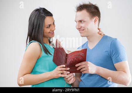 Schwangere Frauen und Ehemänner erkunden ein Heft, in dem Namen ausgewählt werden. Sie pflegen langjährige Traditionen und überprüfen die ersten Ultraschallbilder, die in Th gespeichert wurden Stockfoto