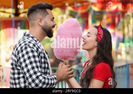Glückliches Paar, das Zuckerwatte auf der Messe isst Stockfoto