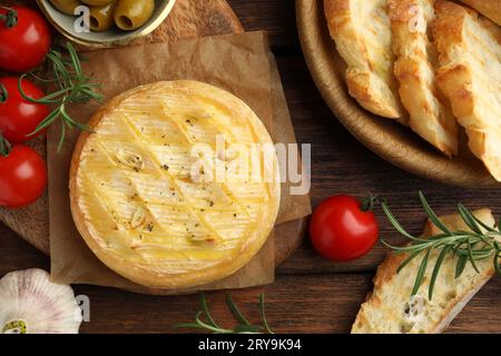 Leckerer gebackener Brie-Käse, serviert auf Holztisch, flach gelegt Stockfoto